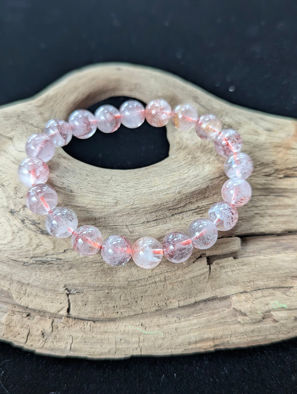 9mm AA Grade Super Seven beaded bracelet displayed on textured wood, showcasing beautiful clarity and red inclusions.