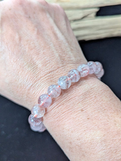 9mm Super Seven gemstone bracelet styled on a wrist, highlighting its organic red and clear visual texture.
