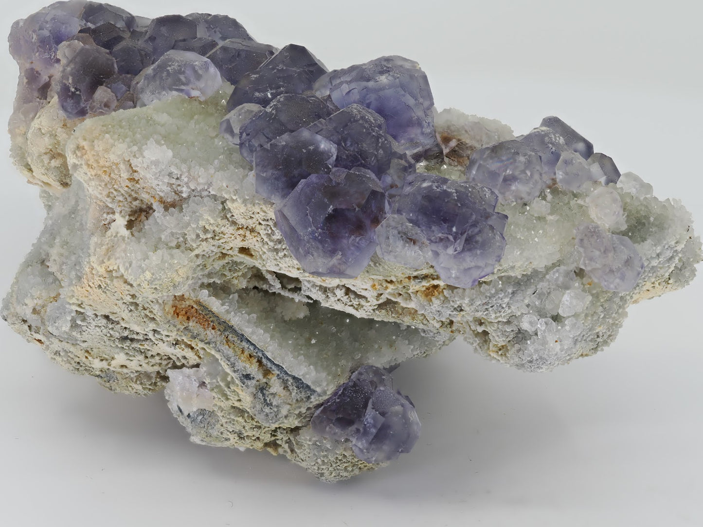 Side view of violet Fluorite cluster showing the depth of the white drusy quartz matrix and crystal relief.