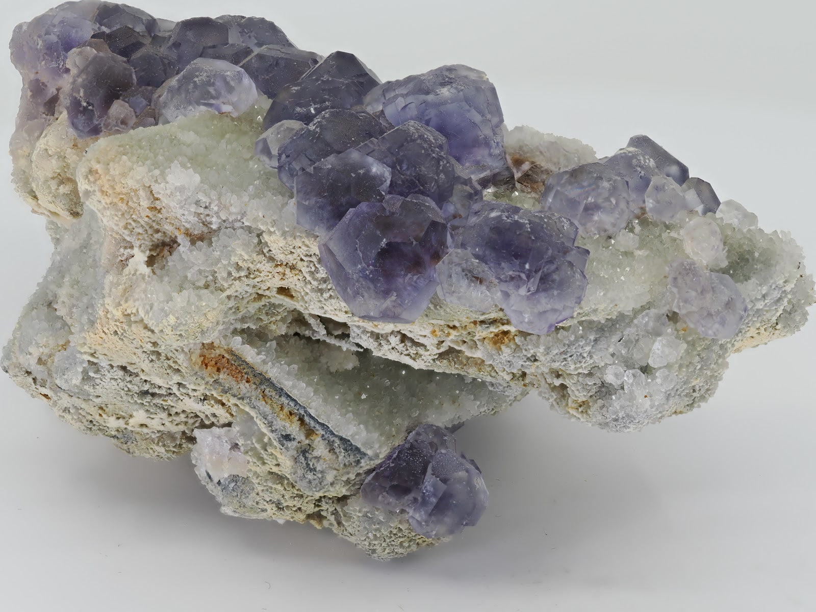 Side view of violet Fluorite cluster showing the depth of the white drusy quartz matrix and crystal relief.