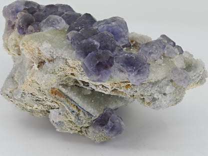 Side view of violet Fluorite cluster showing the depth of the white drusy quartz matrix and crystal relief.