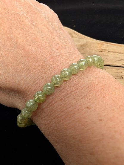 7mm polished Tsavorite beaded stretch bracelet worn on a wrist for delicate size scale.