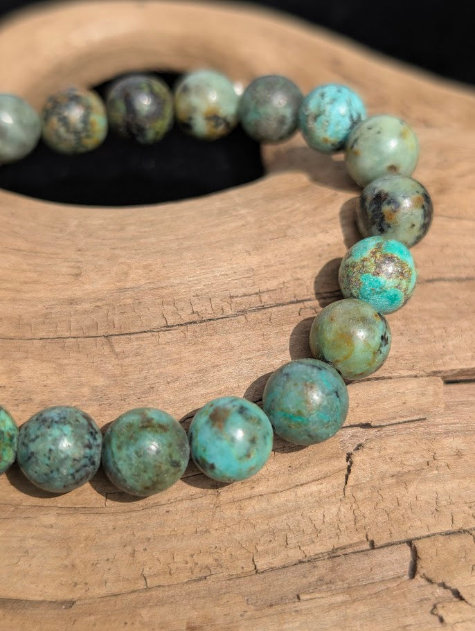 Macro detail of 8mm polished turquoise beads showing natural brown and black host rock matrix patterns.