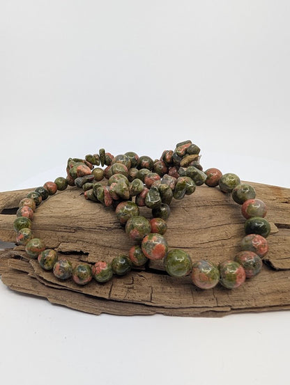 Unakite chip and round bead bracelets displayed on wood