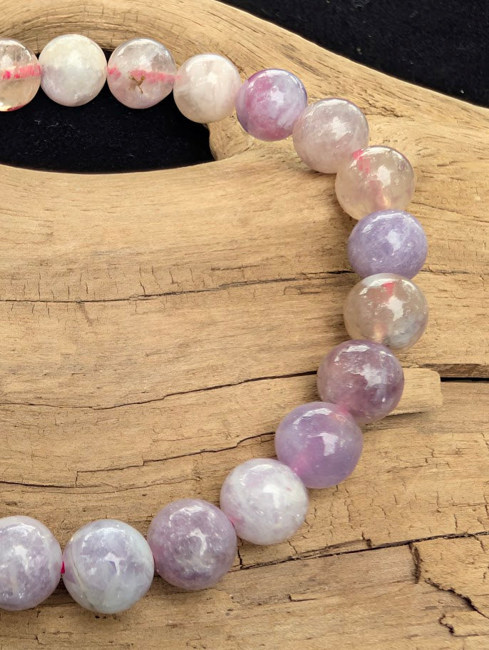 Macro close-up of 8mm polished Unicorn Stone beads highlighting the high-gloss finish and the multi-mineral composite structure of lepidolite and pink tourmaline.