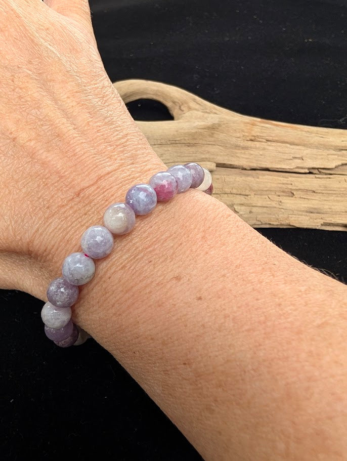 8mm polished Unicorn Stone pegmatite beaded stretch bracelet worn on a wrist for size scale.