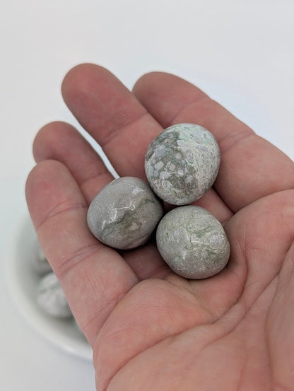 Hand holding Variscite tumbled stones highlighting soft polish and color variation