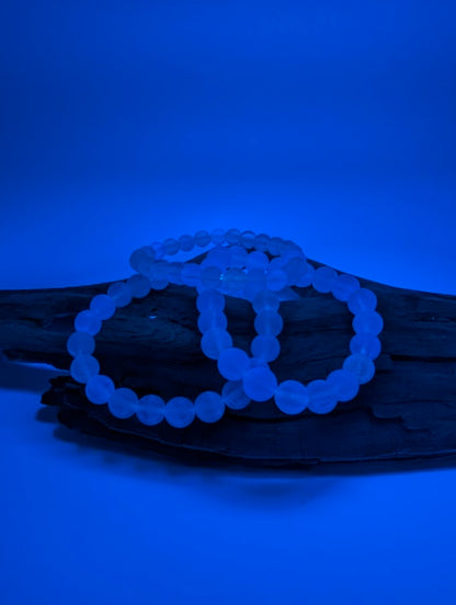 Velvet Fluorite bracelet glowing faint blue under UV light on driftwood background