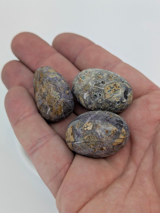 Violet Jasper tumbled stones in hand for size reference