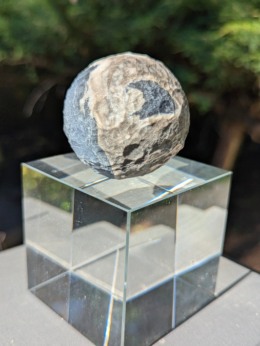A 50 mm (1.97 in) Volcano Agate carved moon sphere featuring complex natural banding and carved craters.