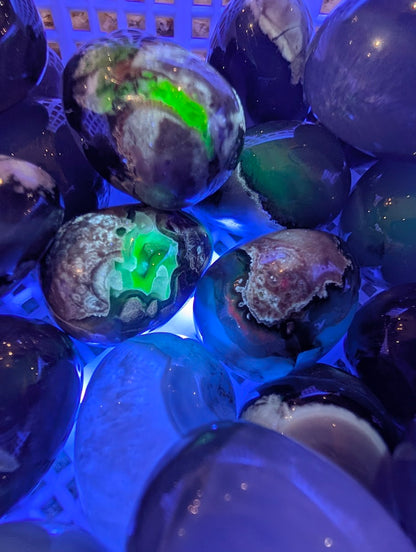 Volcano Agate eggs under 365nm UV light exhibiting intense natural neon green fluorescence.