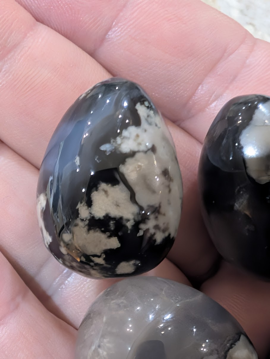 Group of four 1-inch Volcano Agate eggs from Madagascar in natural light showing grey and black plumes.