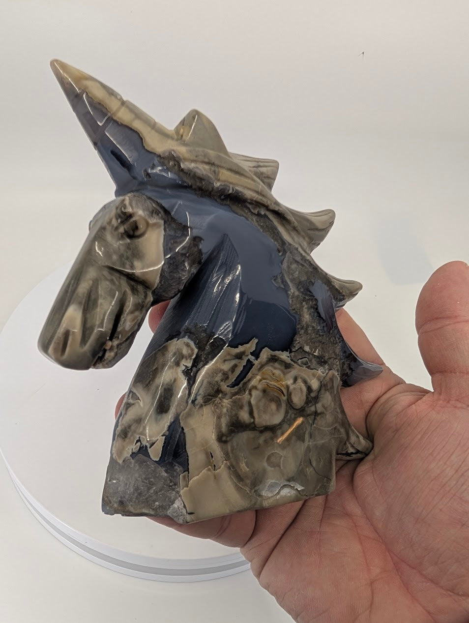 Volcano agate unicorn carving held in hand for size reference