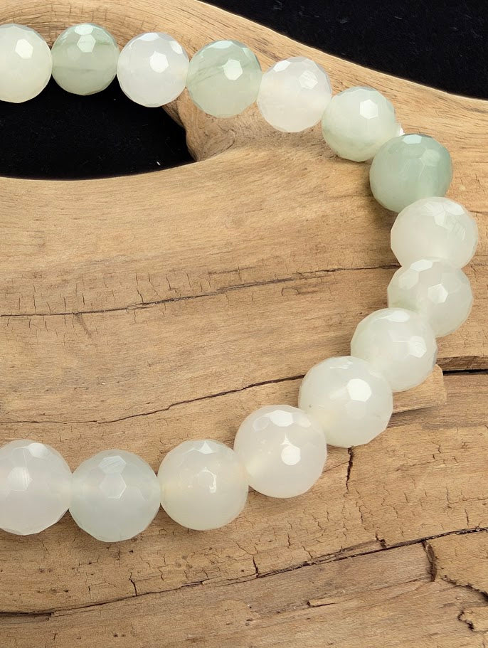 Macro close-up of 8mm faceted White Jade beads highlighting geometric surface cuts and natural pale green inclusions.