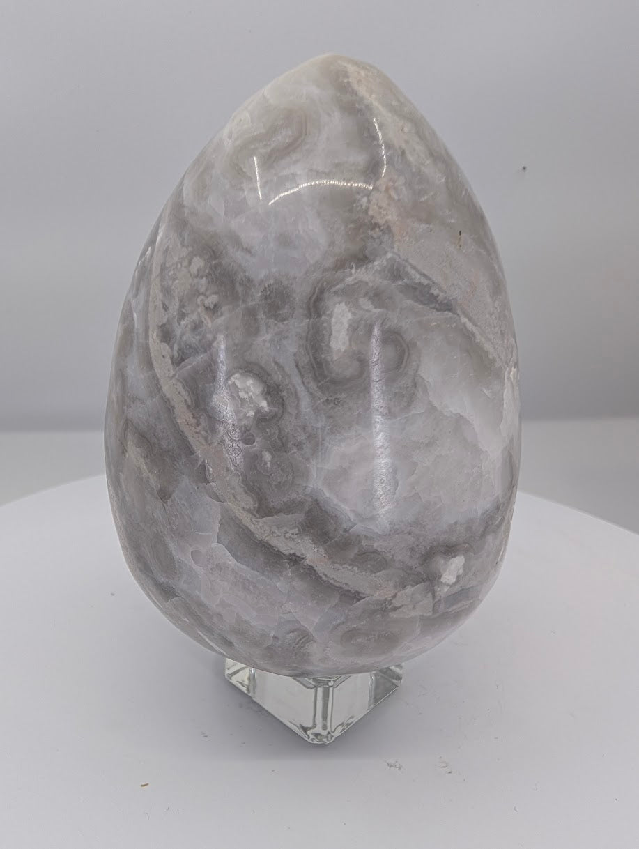 Back view of a polished white Mexican lace agate egg with fine lace patterning