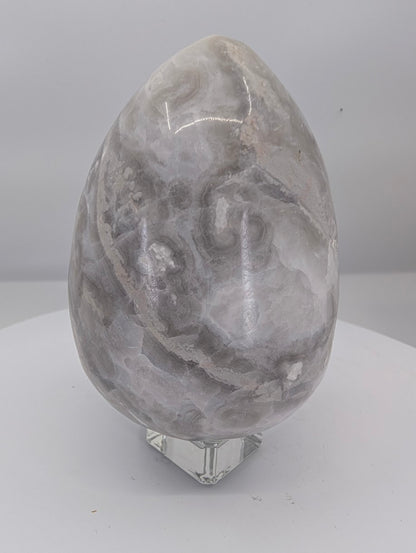 Back view of a polished white Mexican lace agate egg with fine lace patterning
