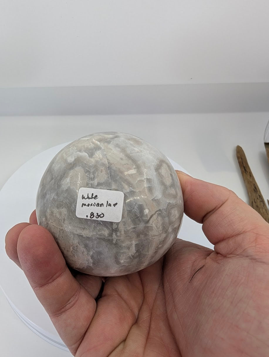 Base view of a polished white Mexican lace agate egg with fine lace patterning