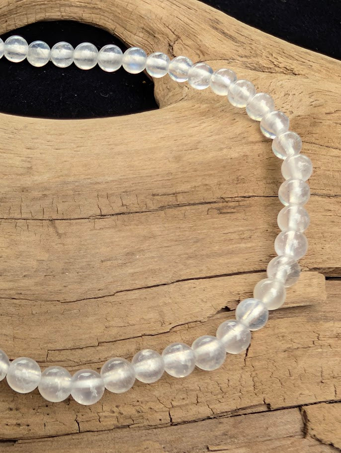 Macro close-up of 4mm polished White Moonstone beads highlighting the high-gloss finish and natural optical flash.