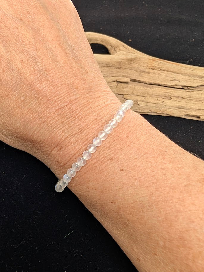 4mm polished White Moonstone beaded stretch bracelet worn on a wrist for delicate size scale.