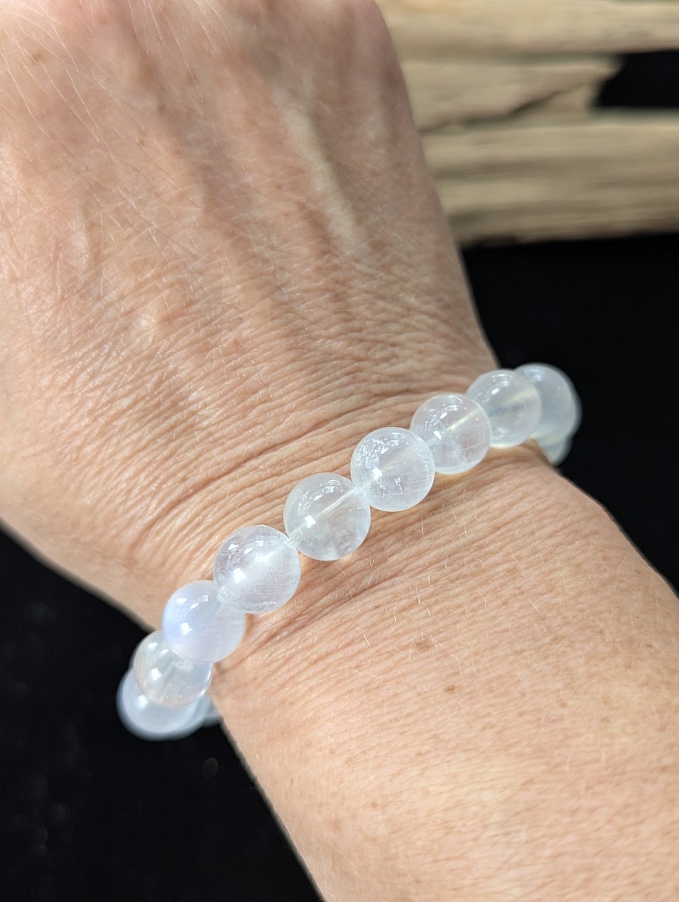 Prominent 10mm White Moonstone gemstone bracelet styled on a wrist, demonstrating size and glowing clarity.