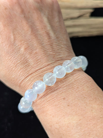 Prominent 10mm White Moonstone gemstone bracelet styled on a wrist, demonstrating size and glowing clarity.