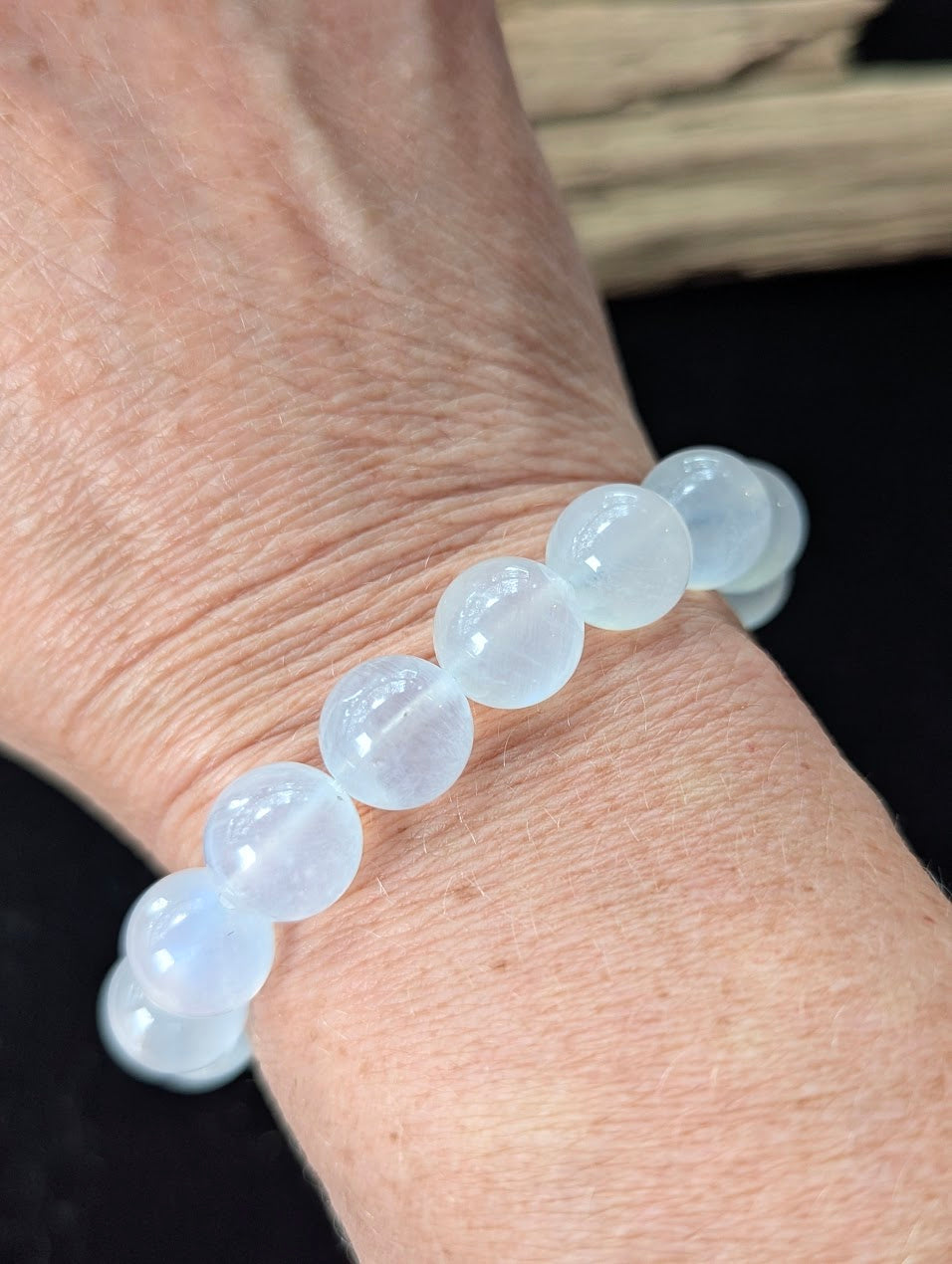 11mm White Moonstone beaded bracelet worn on a wrist, showcasing its substantial size and elegant blue flash.