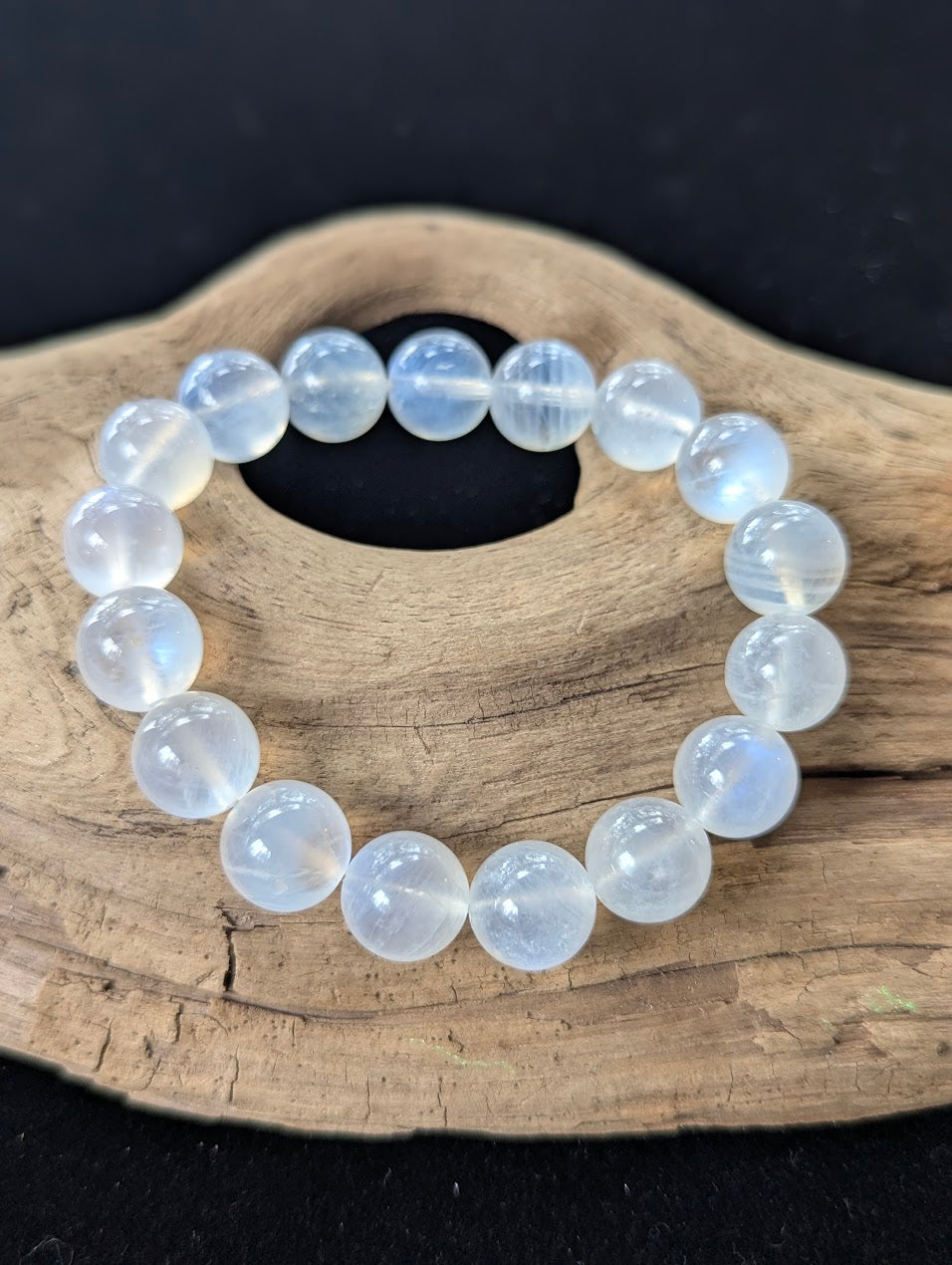 Large 12mm AAA Grade White Moonstone gemstone bracelet displayed beautifully on organic driftwood.