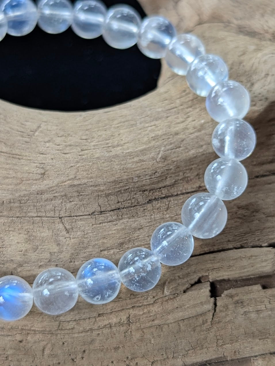 Close-up view of 7mm Sri Lankan White Moonstone beads, highlighting their exceptional transparency and glassy polish.