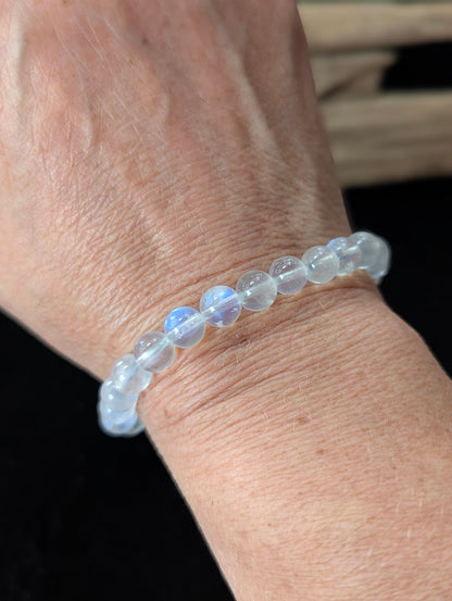 7mm White Moonstone beaded bracelet worn on a wrist, demonstrating the luminous blue flash catching the light.
