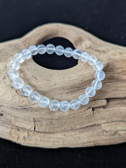 8mm AAA Grade White Moonstone beaded bracelet displayed on textured wood, revealing clear feldspar structure and blue optical sheen.