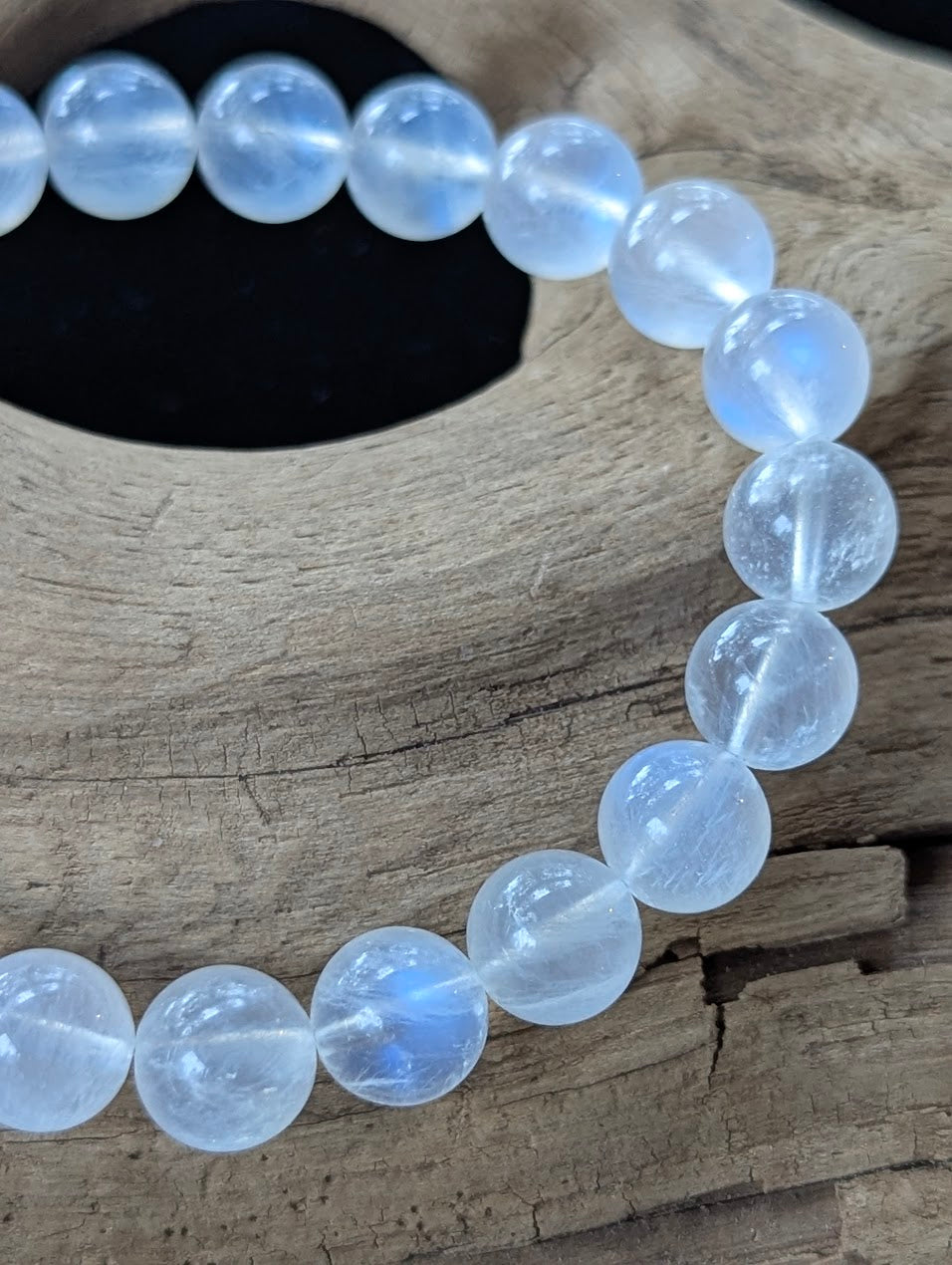 Close-up macro view of 9mm White Moonstone beads displaying water-like clarity and vivid internal blue adularescence.