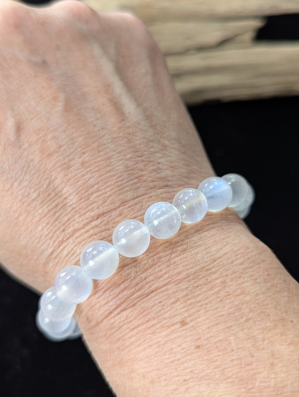 9mm White Moonstone beaded bracelet worn on a wrist, exhibiting radiant optical flash.
