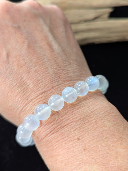 9mm White Moonstone beaded bracelet worn on a wrist, exhibiting radiant optical flash.