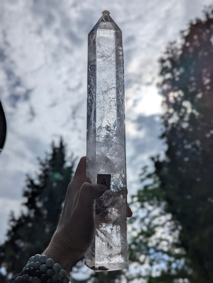 Backlit Garden Quartz Tower A held against the sky showing translucency, internal veils, and natural inclusions