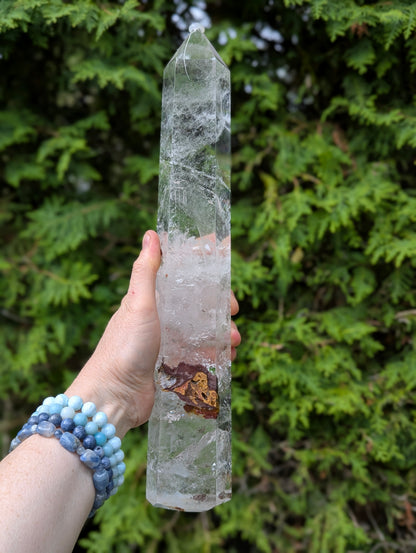 Tower A polished Garden Quartz tower held outdoors showing reverse side with cloudy veils and translucent body