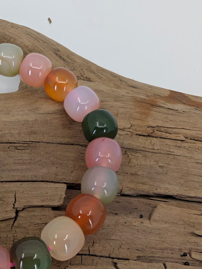 Close-up of Yanyuan agate beads with green, pink, and amber colors