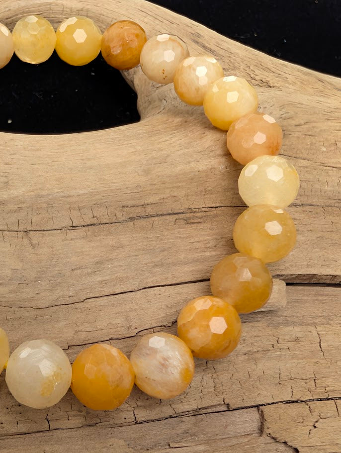Macro close-up of 8mm faceted Yellow Aventurine beads highlighting the geometric cut and subtle natural aventurescence.