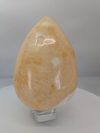 Back view of a large polished yellow calcite egg with natural banding and cloudy translucency