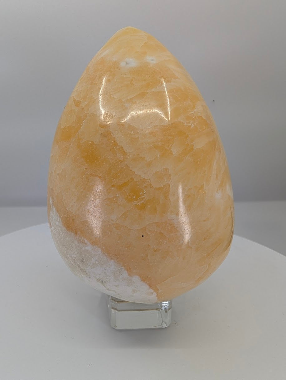 Side view of a large yellow calcite egg showing strong display presence and natural calcite texture