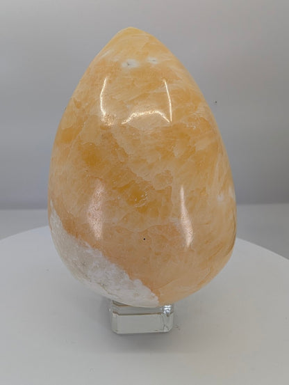 Side view of a large yellow calcite egg showing strong display presence and natural calcite texture
