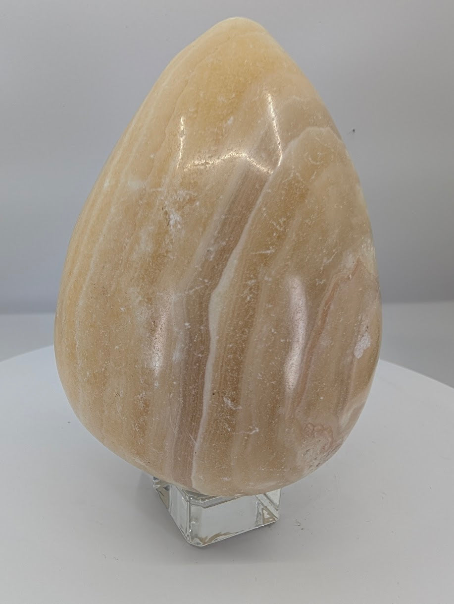 Side view of a large polished yellow calcite egg highlighting layered calcite banding