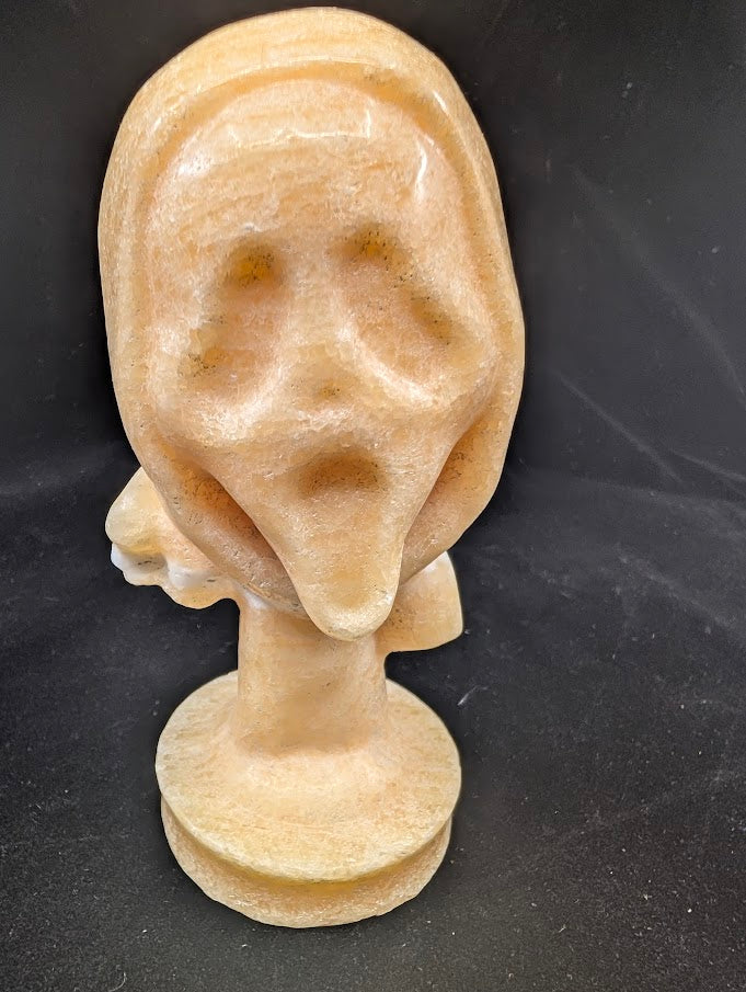 Yellow Calcite “The Scream” carving in lightbox, highlighting translucency