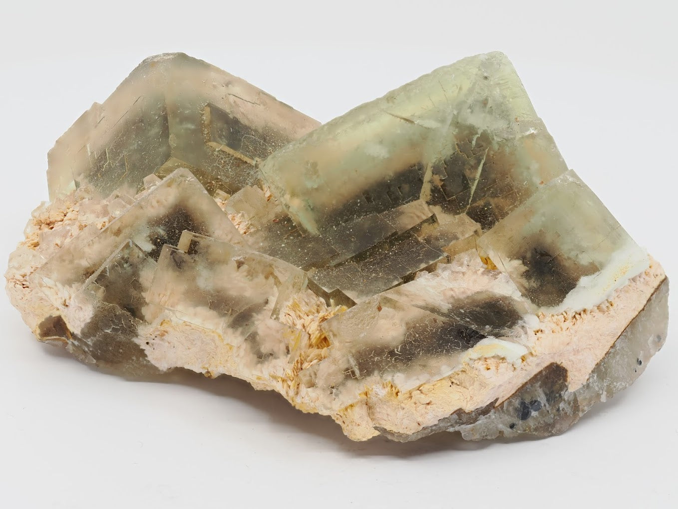 Angled view of golden fluorite crystals sitting on creamy feldspar matrix.