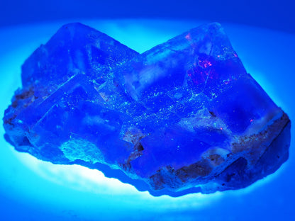 Beijing yellow fluorite glowing bright blue-violet under longwave UV light.