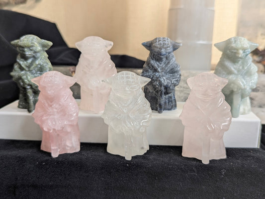 Group of five hand-carved Yoda figurines in Sodalite, Jade, Fluorite, and Quartz on a display stand.