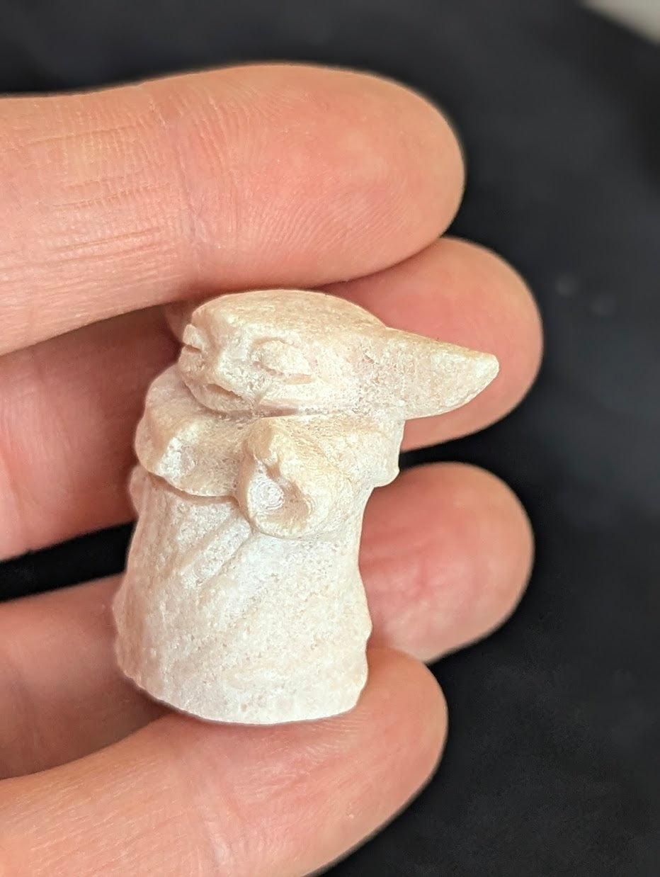 Angled side view of a hand-held Pink Opal Yoda tiny totem.