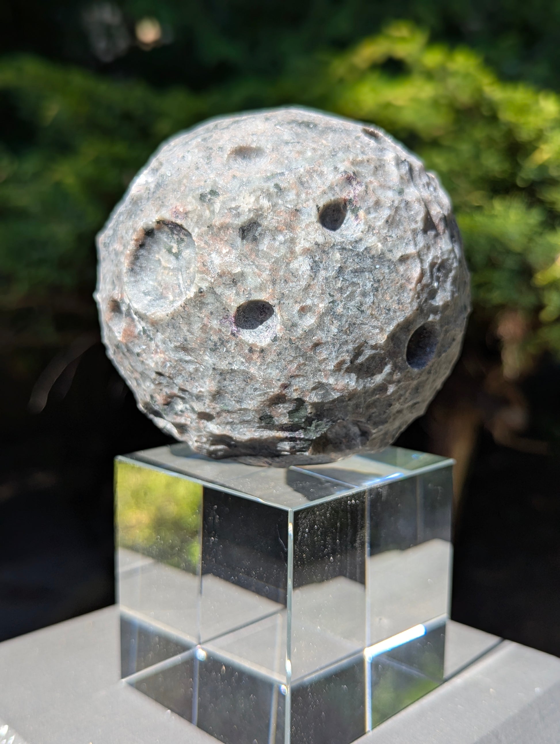 Detailed close-up of the unpolished, hand-carved lunar craters on a 98 mm (3.86 in) Yooperlite moon sphere.