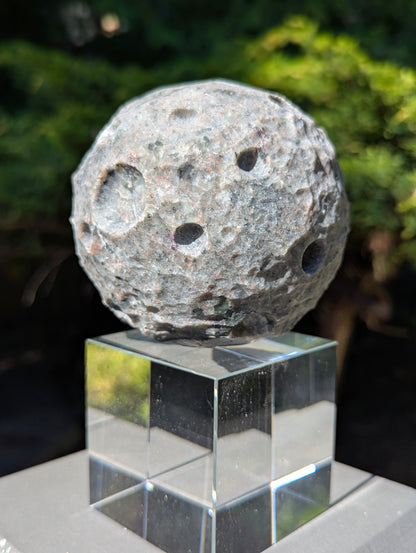 Detailed close-up of the unpolished, hand-carved lunar craters on a 98 mm (3.86 in) Yooperlite moon sphere.