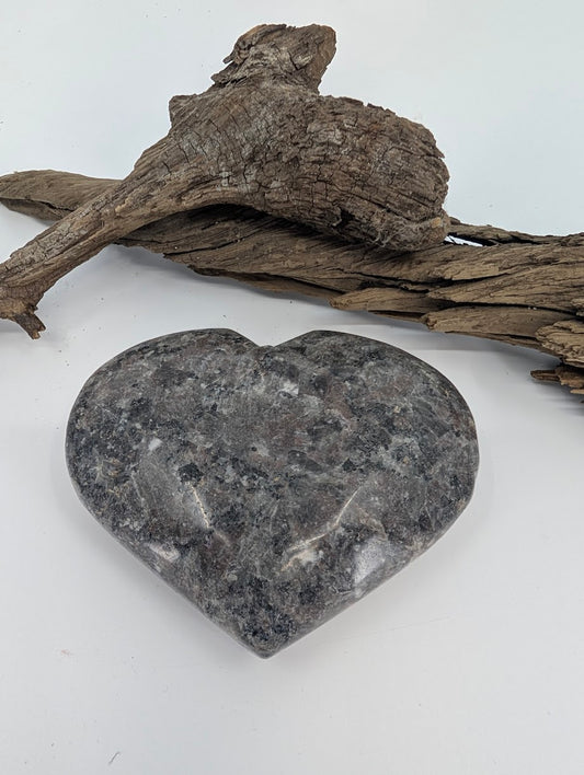 Polished Yooperlite heart on white background, grey stone that glows under UV.