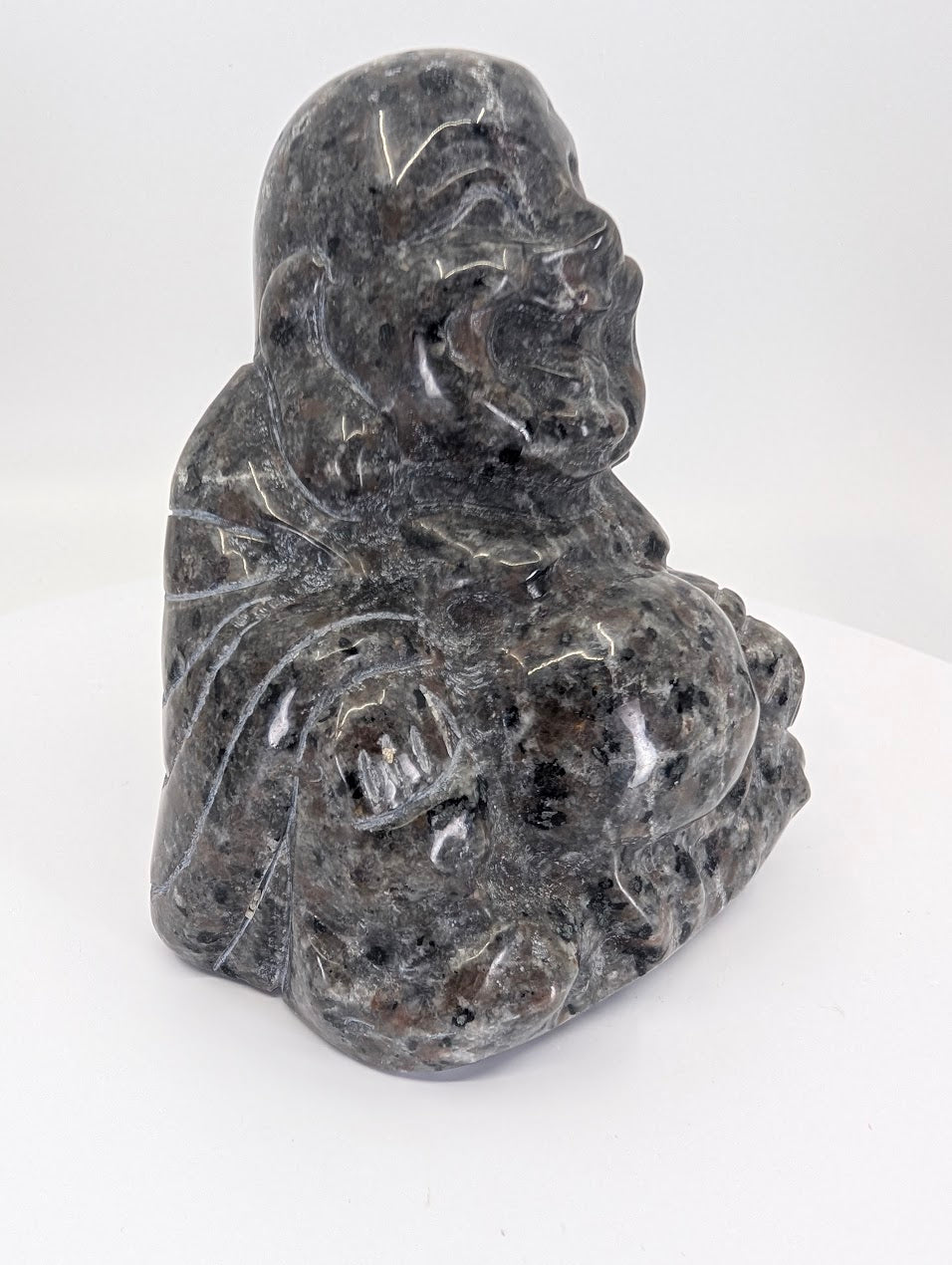 Side view of Yooperlite Laughing Buddha carving showing grey speckled stone